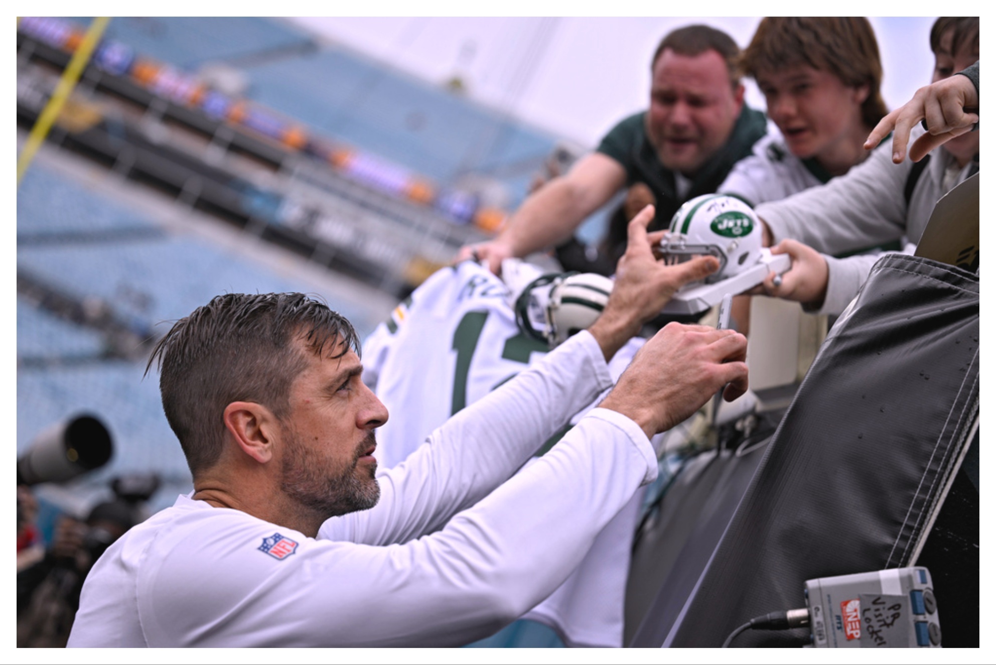 New York Jets quarterback Aaron Rodgers signs autographs for fans before an NFL football game against the Jacksonville Jaguars.